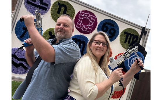 Founders back to back holding tufting guns with Tufting Frame in background showing different tufted circular designs