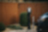 zappi EV charger in black, in front of green box tree and wooden fence