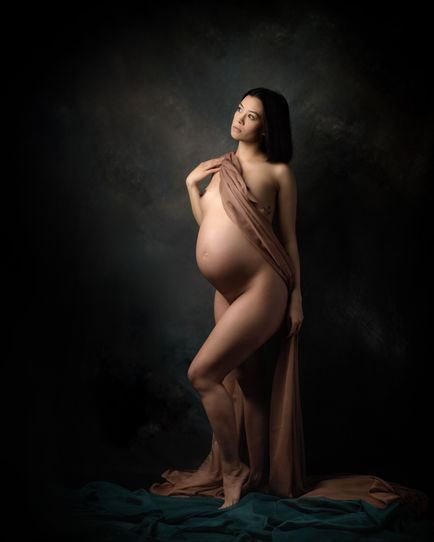 Softly lit color image of pregnant woman draped in a purple cloth