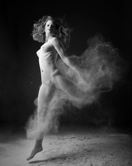 Nude dancer photographed in a sweeping turn, with light painting gentle highlights across her form.