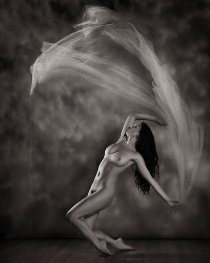 Classical-inspired fine art nude of a dancer balancing in studio light