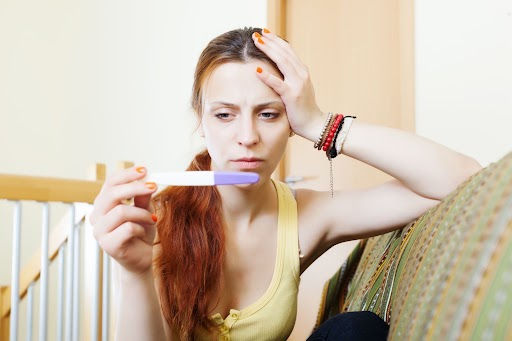 Concerned woman looking at a pregnancy test, illustrating an unexpected pregnancy while using a contraceptive implant.