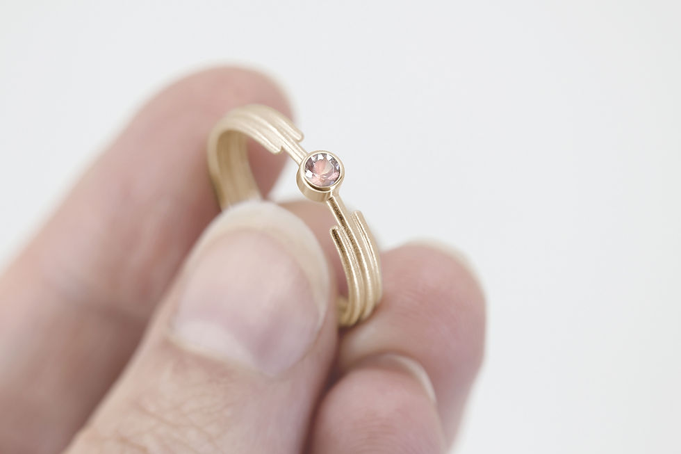 Minimalist Art Deco Fairtrade yellow gold engagement ring with a pink sunstone and grooved band.