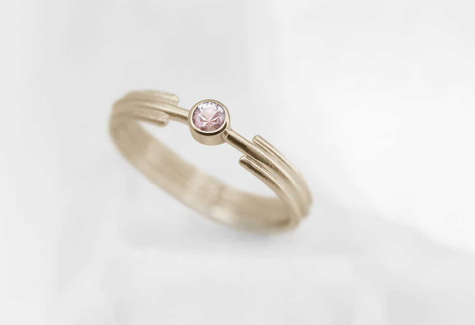 Minimalist Art Deco Fairtrade yellow gold engagement ring with a pink sunstone and grooved band.