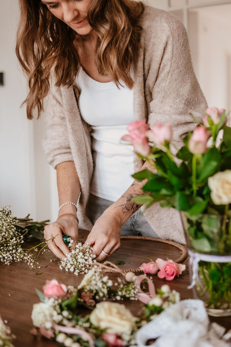 Alina arbeitet an einem Kranz aus frischen Blumen.