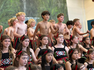 Group of children performing a cultural dance, some shirtless, wearing traditional attire.