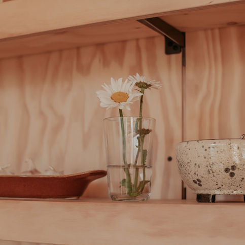 Detail van houten interieur met vaas en schaal in warm licht, rust en eenvoud