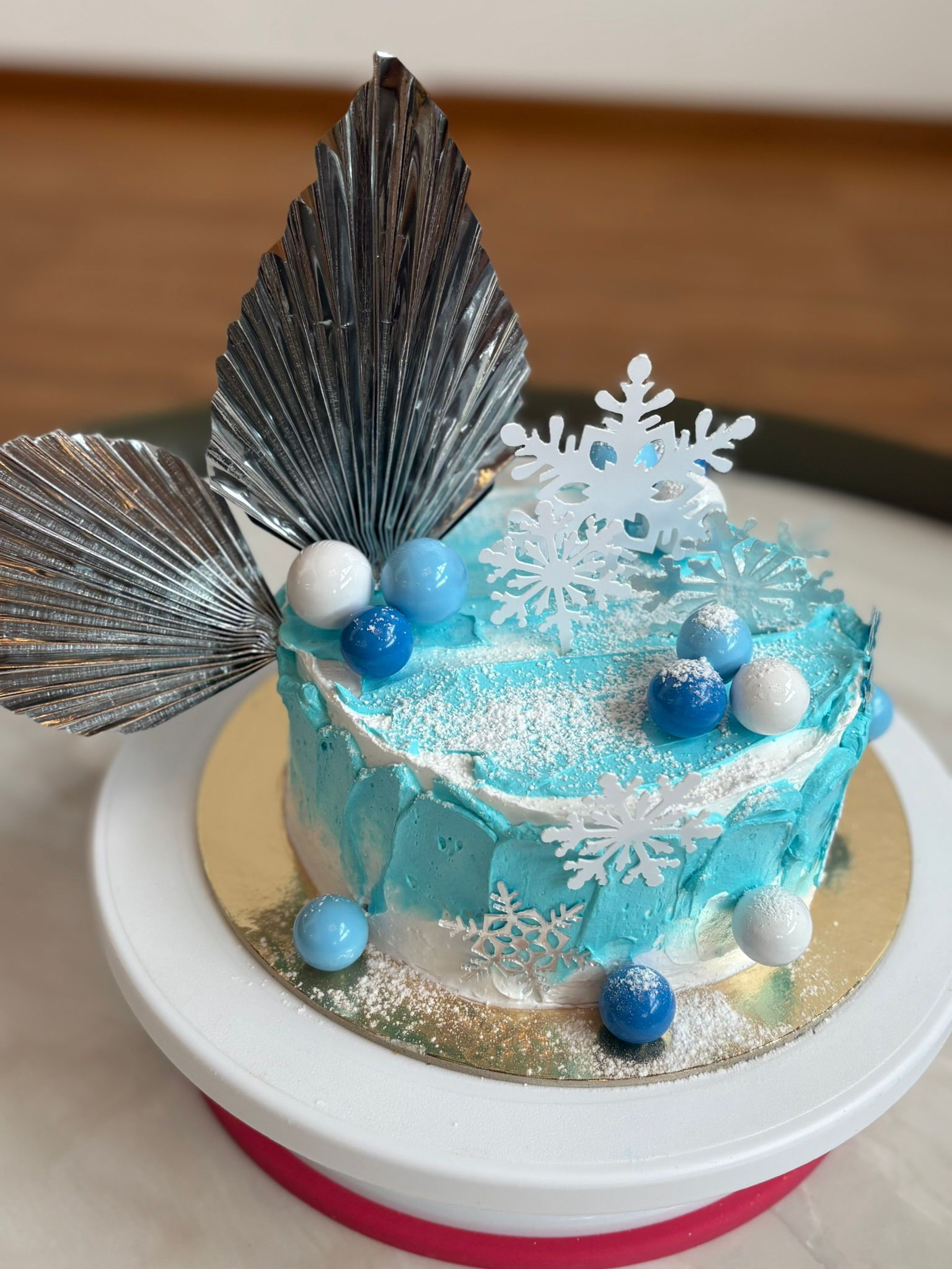Close-up of winter frozen cake showing snowflake toppers, powdered sugar effect, and blue decorative balls