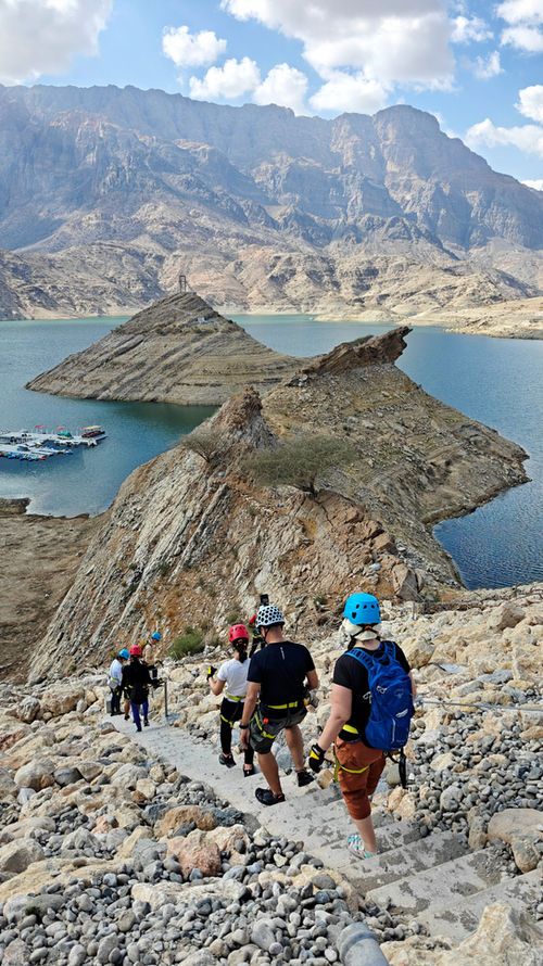 Adventure group hiking above Wadi Dayqah Reservoir during a via ferrata and zipline tour