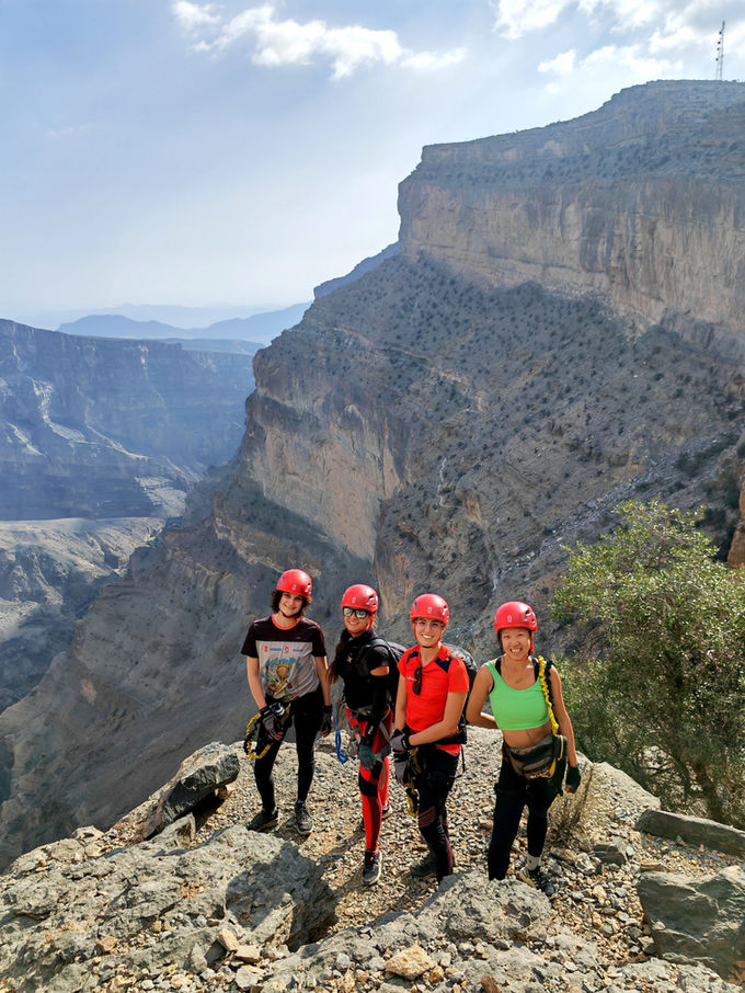 Hiking group overlooking a deep mountain canyon in Oman