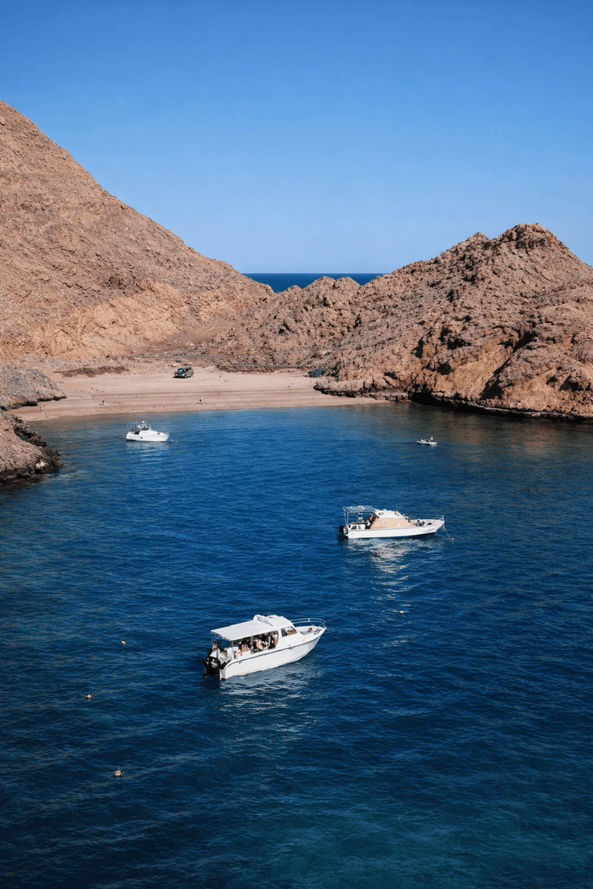 Boats anchored in a sheltered turquoise bay during Bandar Khairan island hopping in Oman