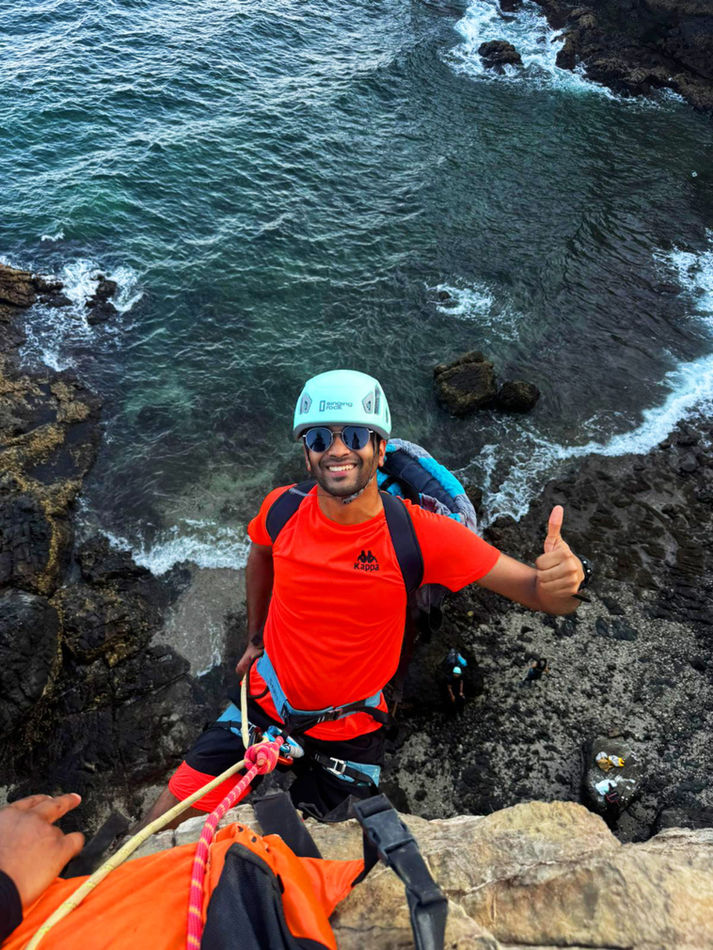 Participant in climbing gear on a sea cliff during the Muscat Sidab abseiling adventure