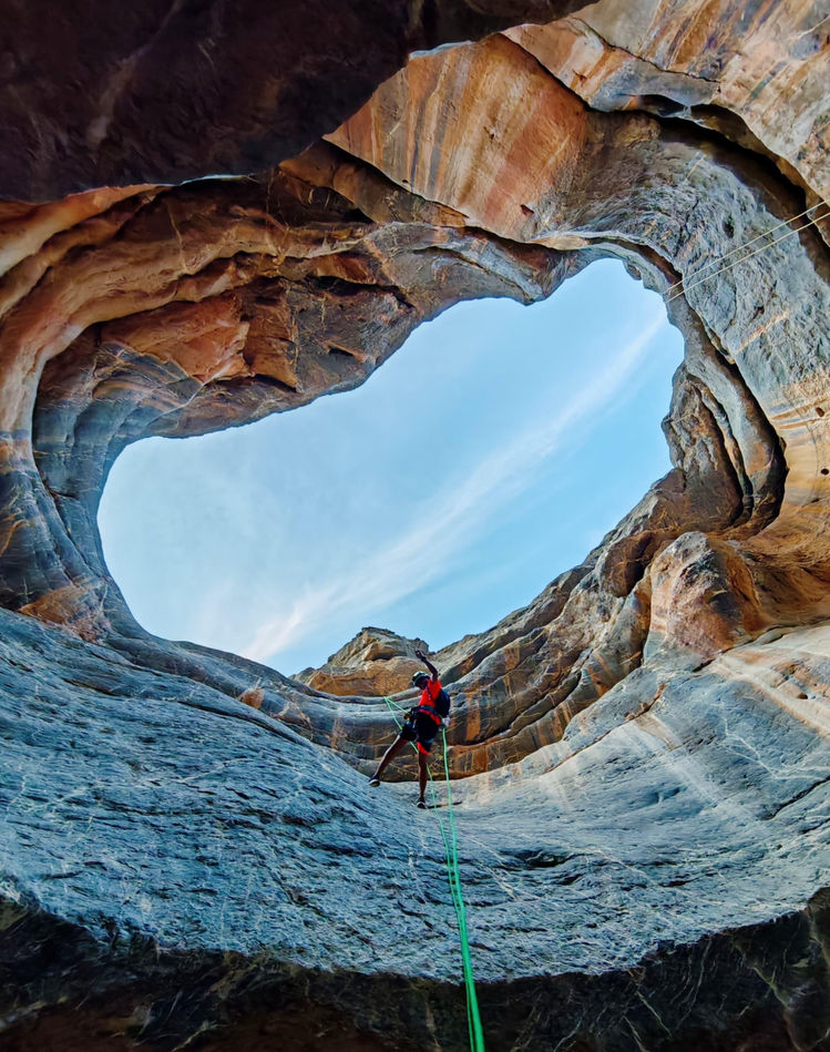 Trainee abseiling through the circular entrance of Sa’al Cave during a 3-hour SRT course in Oman
