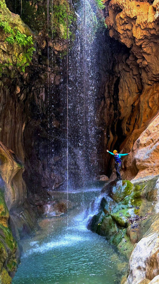 Waterfall dropping into a clear canyon pool on the Wadi Mibam canyoning adventure in Oman