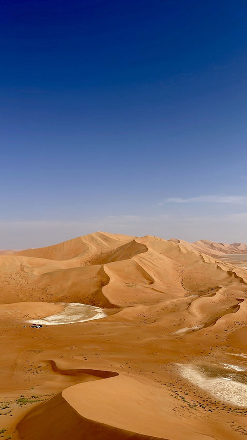 Golden desert dunes beneath a clear blue sky in Oman