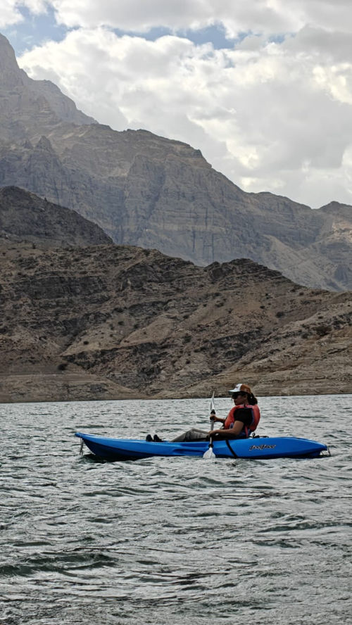 Kayaker exploring Wadi Dayqah Reservoir beneath the Hajar Mountains in Oman