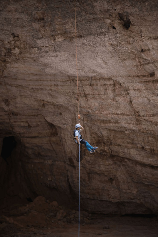 Caver descending by rope inside Majlis Al Jinn Cave during an SRT expedition in Oman