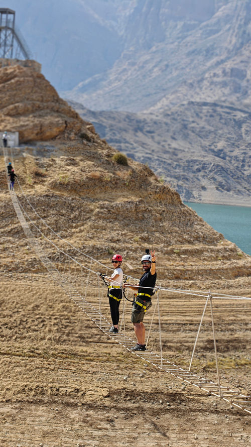 Participants crossing the Wadi Dayqah via ferrata route above the reservoir in Oman