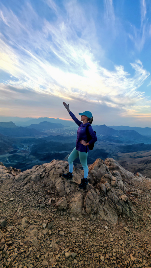 Hiker celebrating on a mountain viewpoint during the Sa’al Steps hike near Muscat, Oman