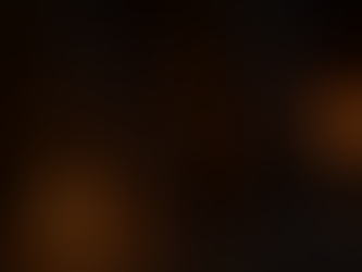 Witch’s broom at a stone floored cottage doorway with a candle burning and a fire glowing inside.