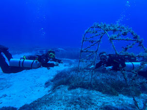 Zwei Taucher in Sidemount erkunden eine Unterwasserstruktur auf einem Tauchplatz im Mittelmeer während einer PADI Divemaster- und Deep-Diver-Ausbildung auf Zypern.
