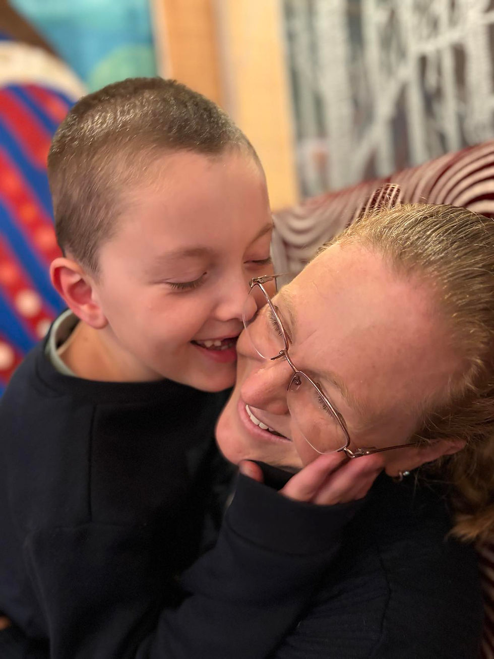 Child and adult hugging and smiling in a colourful room.