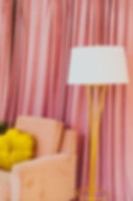 Peach armchair, pink curtain, and a yellow standing lamp