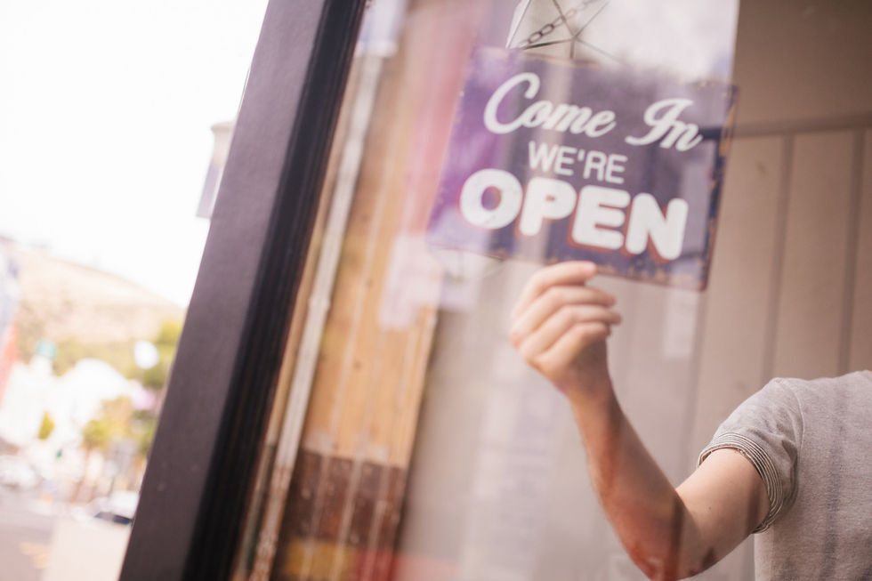 A person flipping a Come In We're Open sign