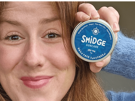 woman holding a tin of Smidge sunscreen next to her face