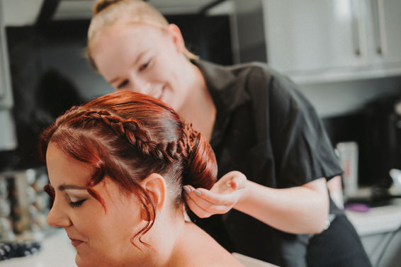 Hair stylist braiding bride's hair for wedding