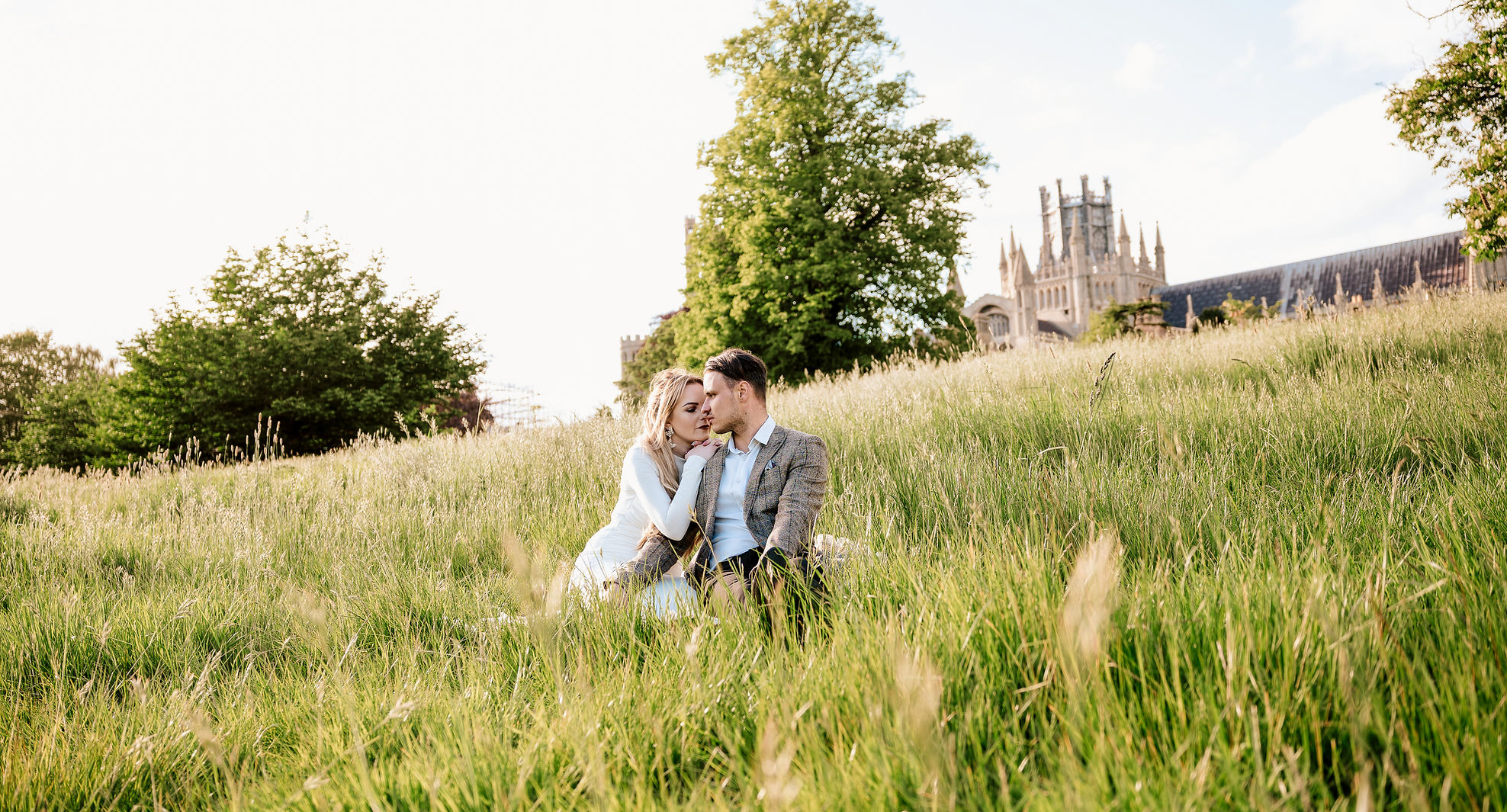 Couple embracing in field, cathedral backdrop, Cambridge wedding photographer, LP wedding photography