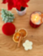 Christmas Spice Floating Rosette Candle with a cinnamon stick, oranges, a poinsettia and a red Christmas ornament