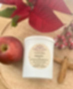 Apple + Cinnamon Candle for Christmas. A red apple, cinnamon sticks, cranberries and a poinsettia as a background.