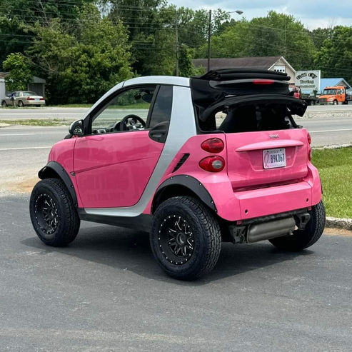 Pink Lifted Smart Fortwo convertible sitting on large tires; BRAAP Store Smart Car Lift Kits.