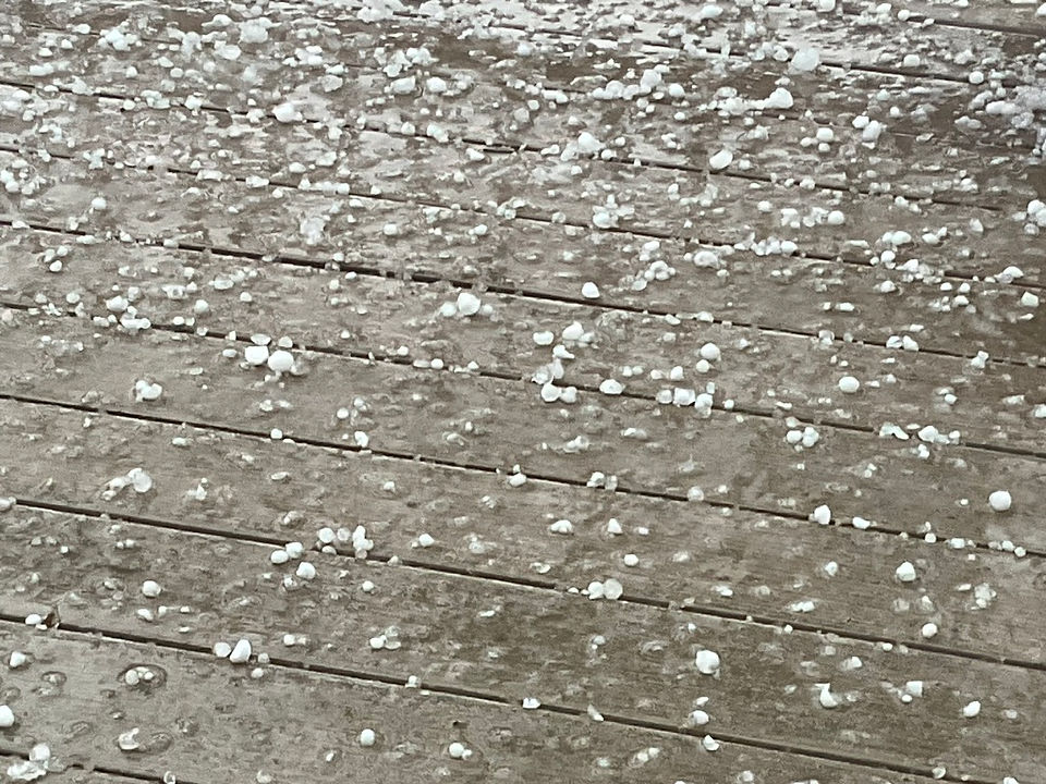 Pea-size hail covers wooden decking.