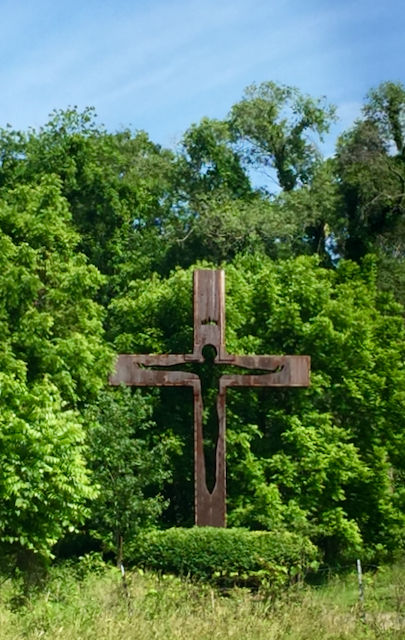 A metal Cross highlighted by trees