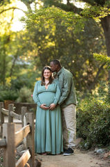 Couple embracing outdoors, with the husband gently holding his pregnant wife as she cradles her belly taken by Sacramento photographer Kristina Martin Photography.
