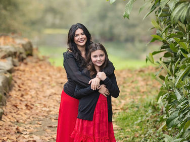 Sacramento family posing together during a fall session at The Iris Farm surrounded by autumn leaves and greenery, photographed by Kristina Martin Photography.