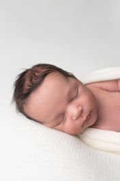 A gallery of newborn session images featuring a swaddled baby in simple, cozy setups. The photos capture a variety of angles, showing the baby peacefully resting in natural, comfortable poses. Some images are taken on a soft white backdrop, while others include a blue background or warm, textured blankets taken by Sacramento Maternity and Newborn photographer Kristina Martin Photography.