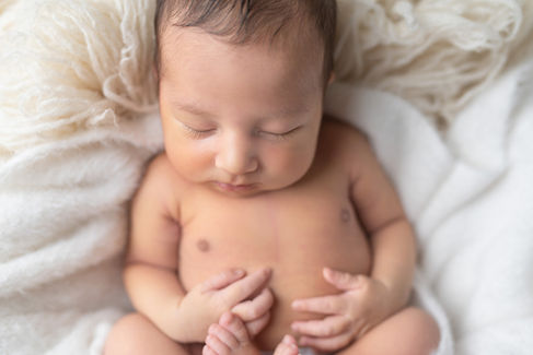 Sweet newborn baby boy peacefully sleeping in a cozy studio setting, wrapped in soft neutrals of cream and white, with delicate details captured like tiny toes, hands, and lashes. Family photos included tender moments with mom and dad. Taken by the best maternity and newborn photographer in Sacramento, Kristina Martin Photography.