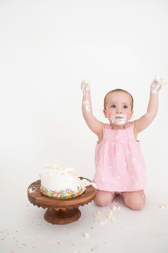 Roseville studio one year milestone session featuring a baby girl, simple white cake smash setup, natural sibling moments, and soft backlit family photography by a Sacramento photographer.