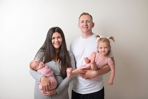 Sacramento newborn photographer capturing a soft in-home newborn session with a baby girl, natural light portraits, neutral wraps, and sweet sibling and family moments.