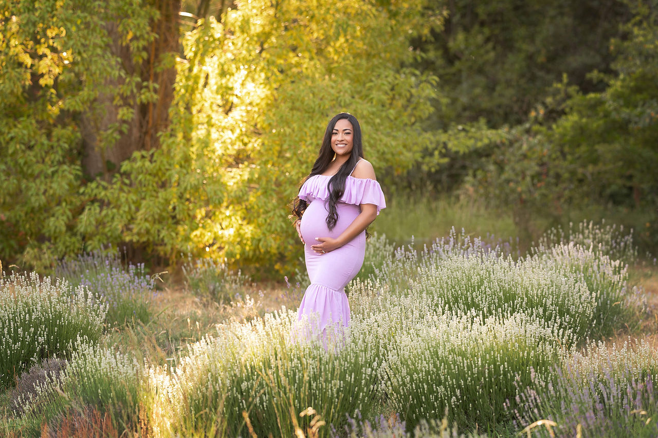 Pregnant woman in maternity gown at lavender farm captured by best Sacramento maternity photographer, featuring romantic outdoor maternity portraits in golden light.