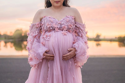 A beautiful maternity photography session taken by the best Sacramento maternity photographer, featuring a glowing mother-to-be in stunning settings. The images showcase a mix of posed and candid moments with her family, including her partner and children, set against rustic barns, lush greenery, and serene sunset backdrops. The session highlights elegant maternity gowns in shades of blue and pink, capturing the joy, love, and anticipation of this special time.