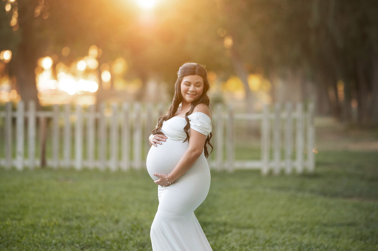 Beautiful summer maternity photoshoot at Gibson Ranch with Valentina, showcasing a glowing mom-to-be in two elegant gowns from the client closet, surrounded by warm sunset light, captured by Sacramento's best photographer, Kristina Martin.
