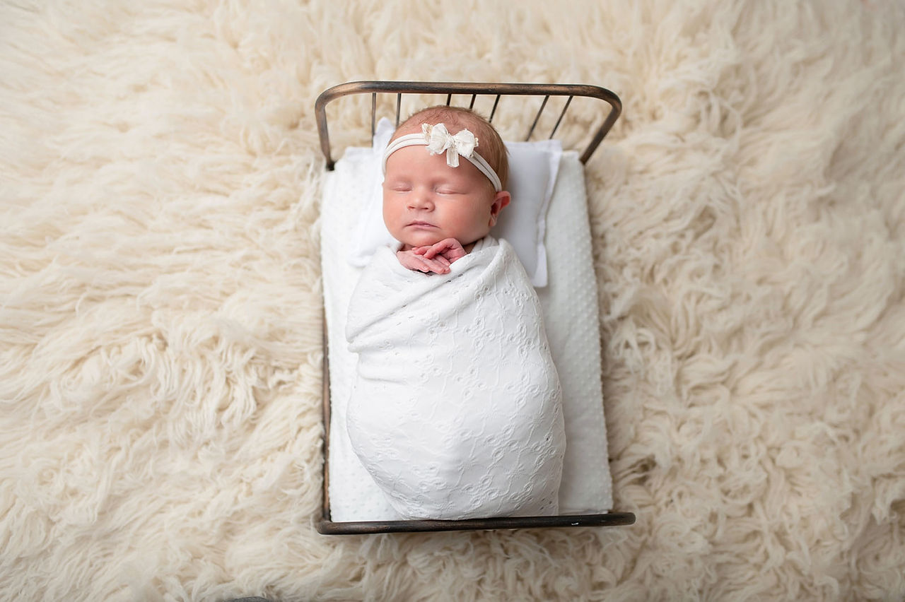 Sacramento newborn photographer capturing a soft in-home newborn session with a baby girl, natural light portraits, neutral wraps, and sweet sibling and family moments.