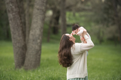 Family session at a blooming botanical garden in Sacramento featuring parents with their three month old baby girl, soft floral backdrops, candid moments, and natural light photography by a local Sacramento baby and family photographer.