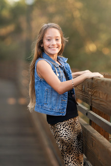Family photography session at the Citrus Heights Nature Preserve featuring a family walking along a wooden bridge surrounded by trees and warm evening light.