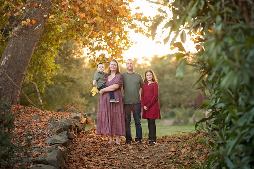 Family of four posing together during a fall family photography session surrounded by golden trees at the Iris Farm in Loomis, California.