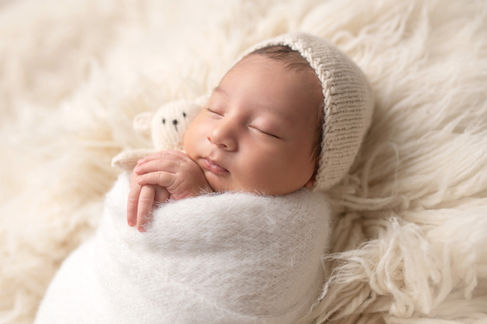 Sweet newborn baby boy peacefully sleeping in a cozy studio setting, wrapped in soft neutrals of cream and white, with delicate details captured like tiny toes, hands, and lashes. Family photos included tender moments with mom and dad. Taken by the best maternity and newborn photographer in Sacramento, Kristina Martin Photography.